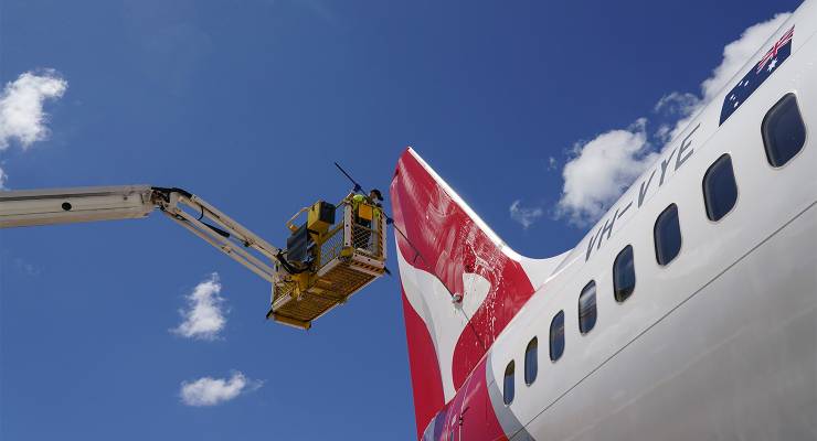 An aircraft appearance crew member cleans a Qantas plane (Image: AAP/Reuters/Loren Elliott)